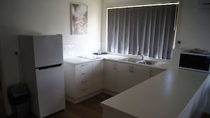Uma cozinha compacta com geladeira, pia e micro-ondas.