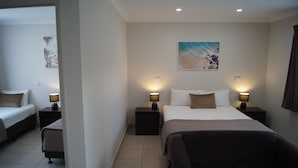 Quarto de hotel com uma cama grande, duas mesas de cabeceira com luminárias, um sofá pequeno e um quadro na parede.