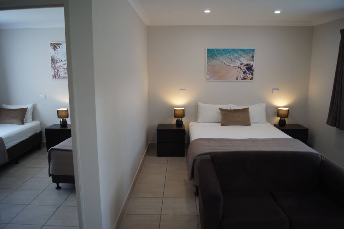 Une chambre d’hôtel avec un grand lit, deux tables de chevet avec des lampes, un petit canapé et un tableau au mur.