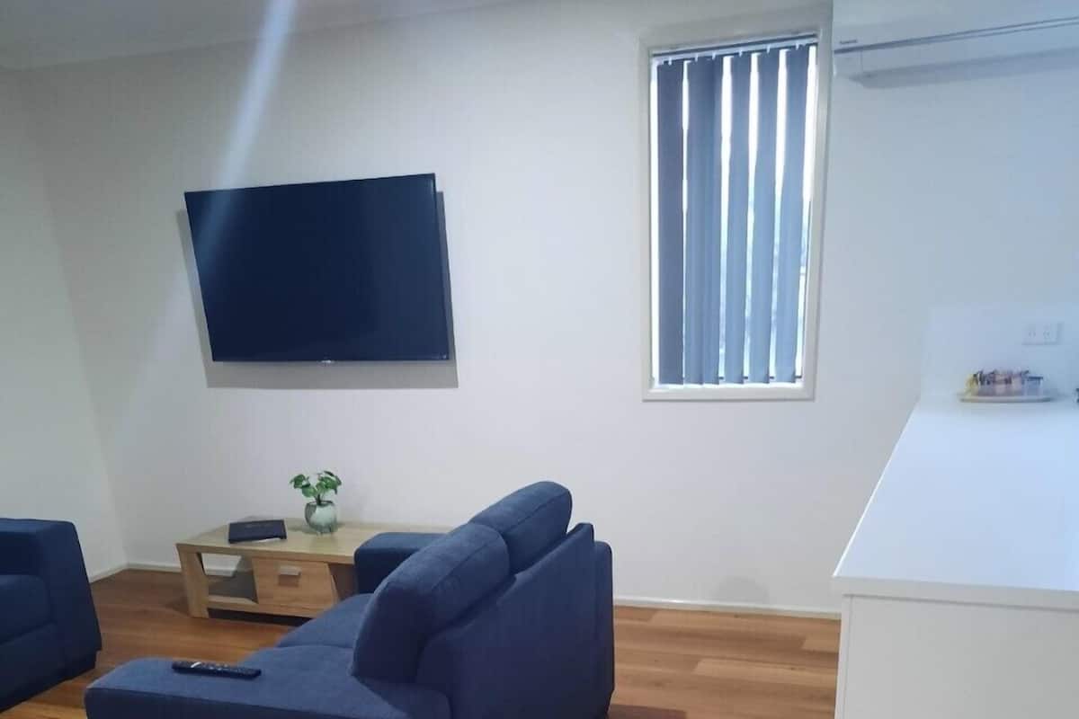 Un salon moderne avec un grand canapé bleu foncé, une table basse en bois et un téléviseur à écran plat fixé au mur.