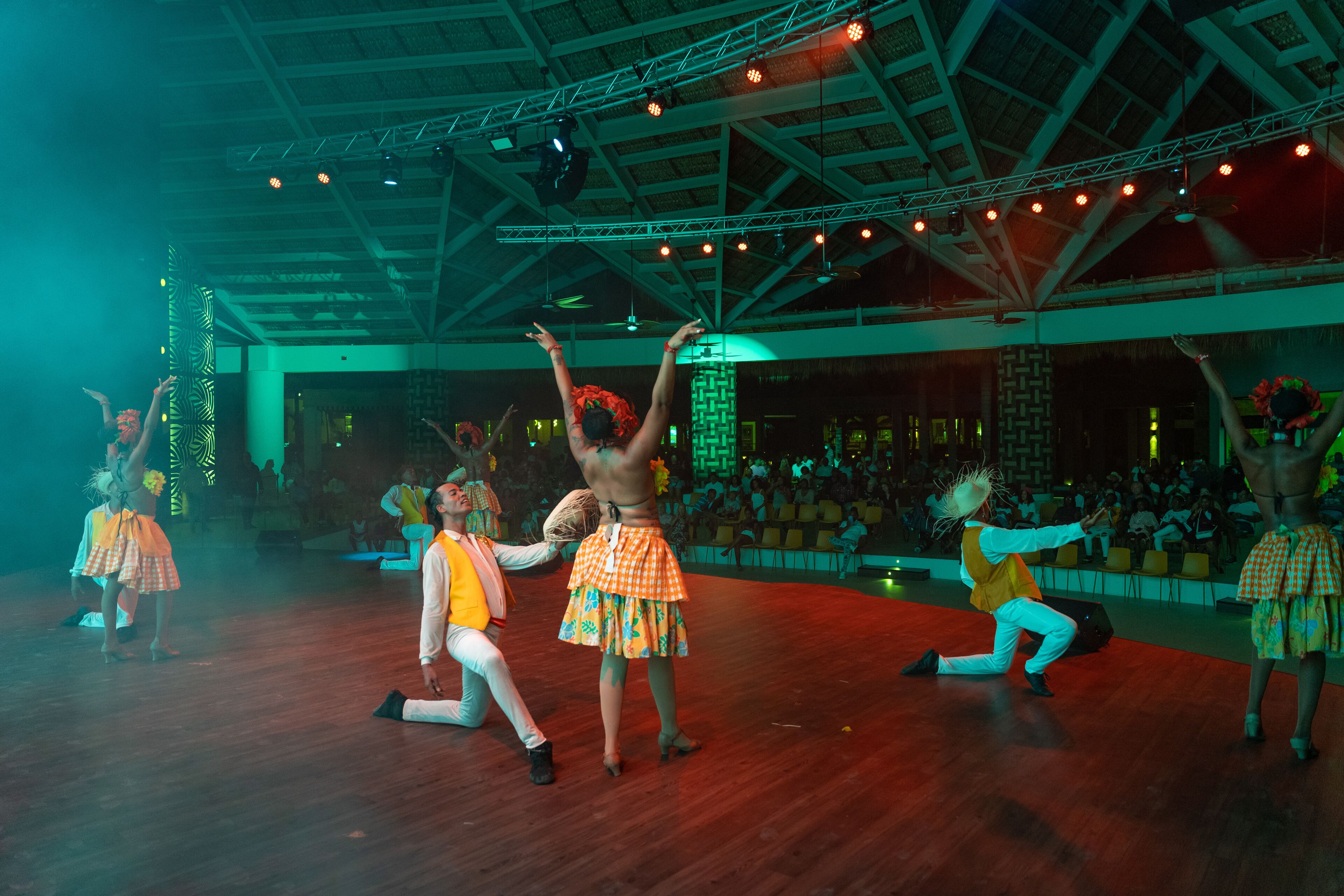 Una función de danza en un amplio salón con techo alto y suelo de madera.