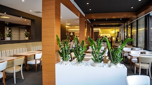 A modern restaurant with wooden accents, white seating, and green plants. - Oxygen Lifestyle Hotel  (Rimini)