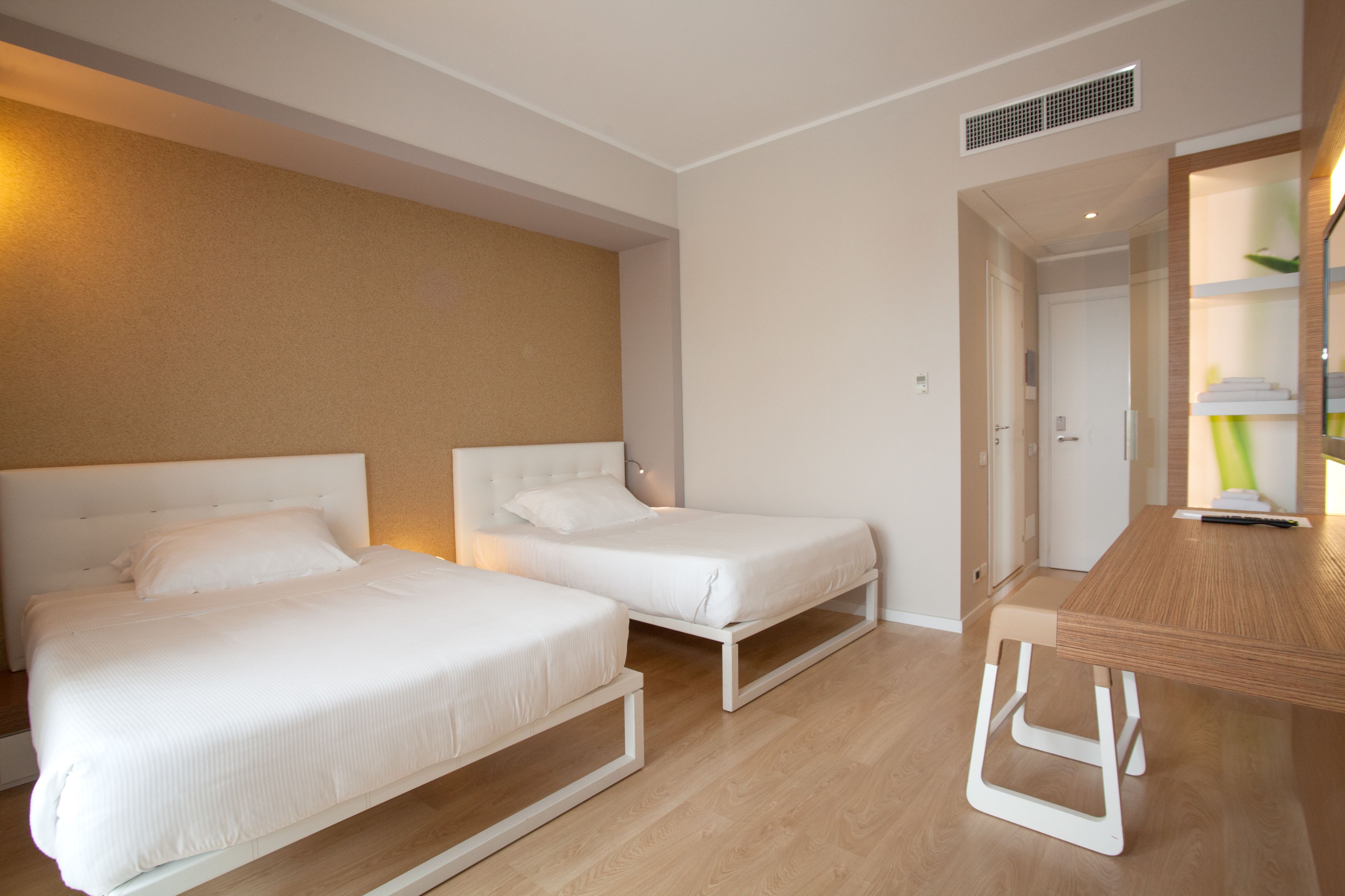 Una habitación de hotel con dos camas individuales, una mesa de madera y un espejo.