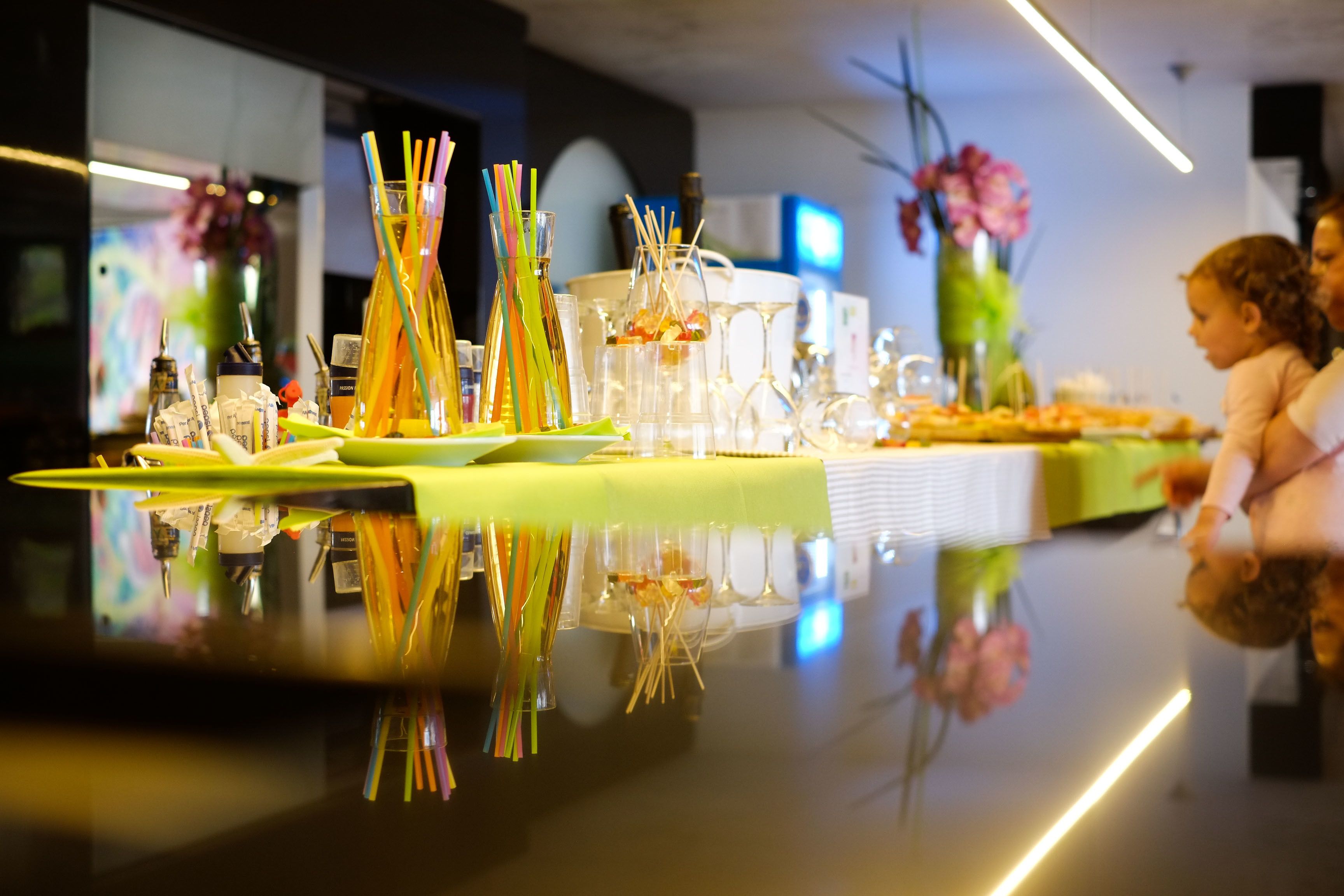 A bar area with a reflective surface, glassware, and colorful straws.