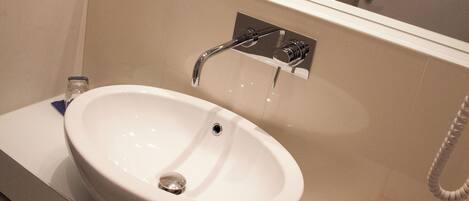 Un baño con lavamanos blanco, espejo y ducha.