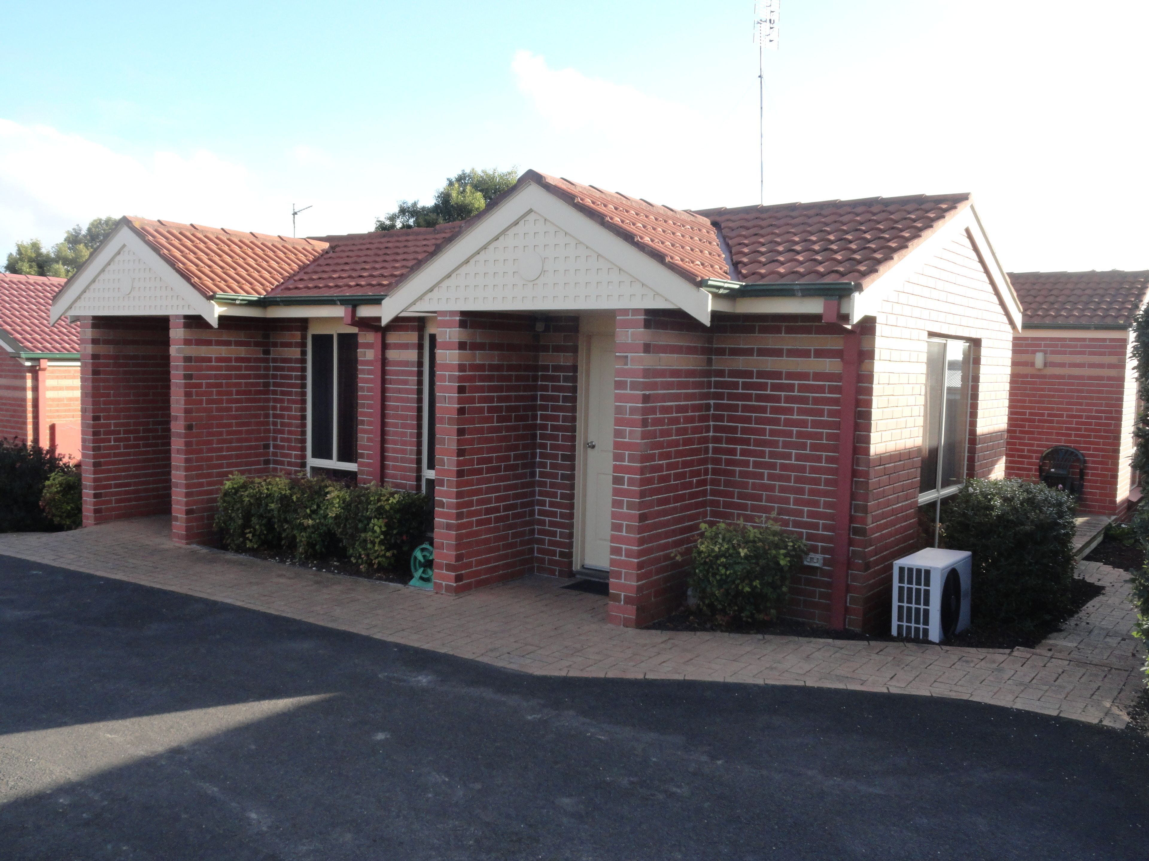 A row of small, brick houses with red-tiled roofs and a central entrance.