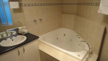 A bathroom with a bathtub, two sinks, and a mirror.