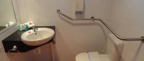 Une petite salle de bain avec un lavabo, des toilettes et une barre d’appui.
