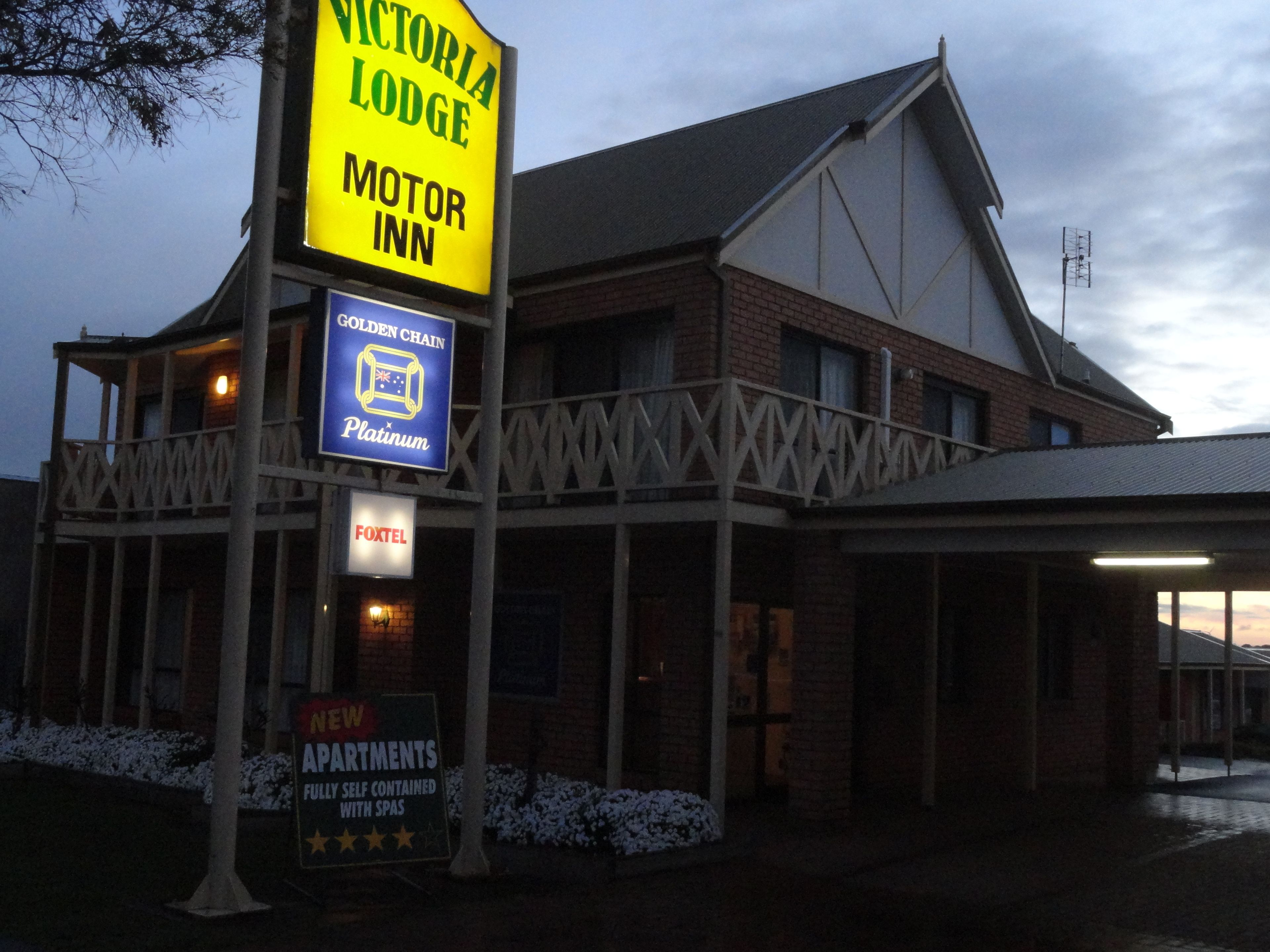 A building with a sign for Victoria Lodge Motor Inn, a sign for Golden Chain Platinum, and a sign for FoxTel.