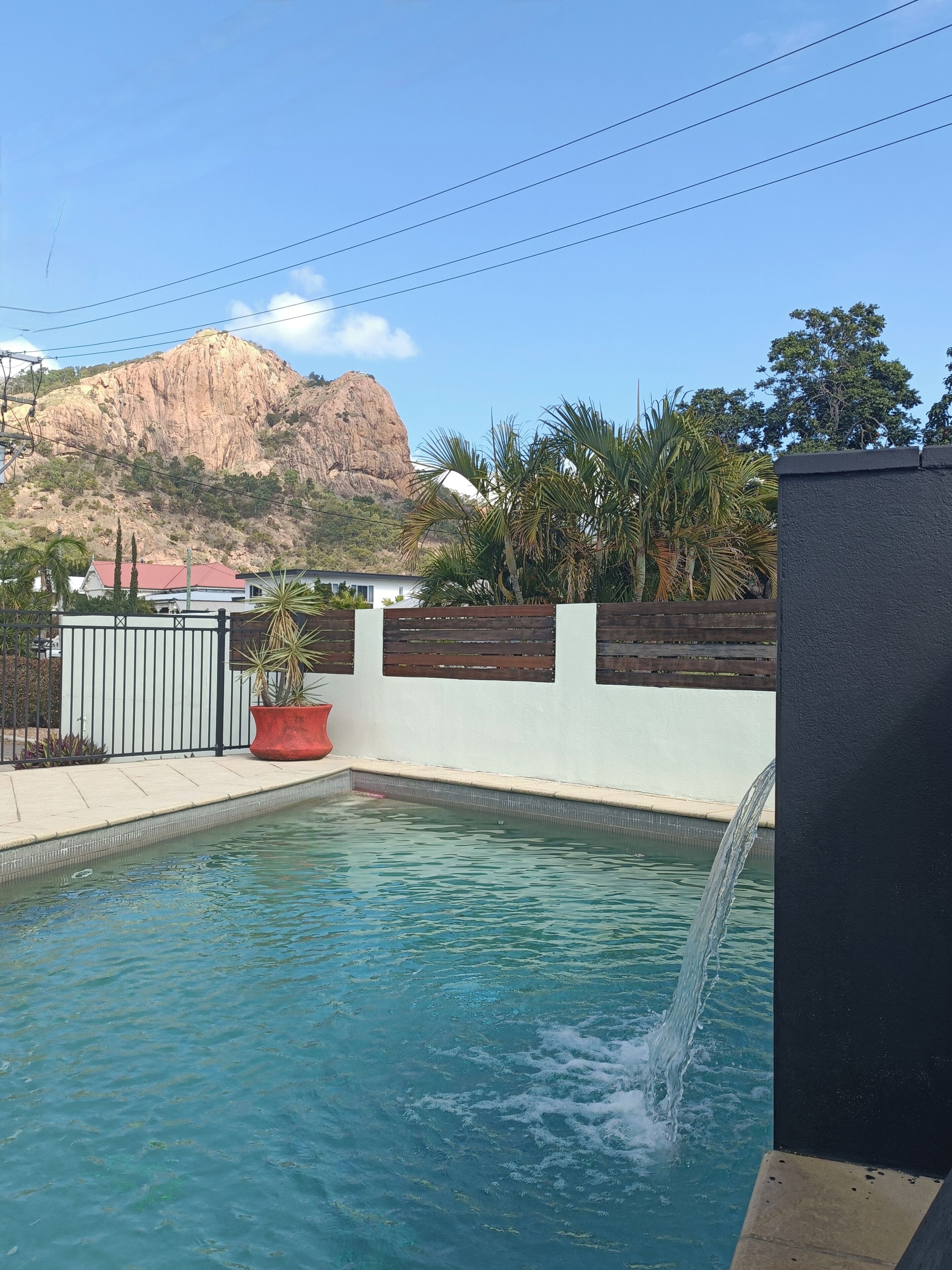 Una piscina al aire libre, sombrillas, sillones reclinables de piscina