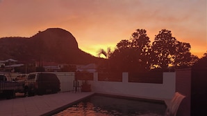 Piscina com cascata, cercada por uma parede branca e um muro.