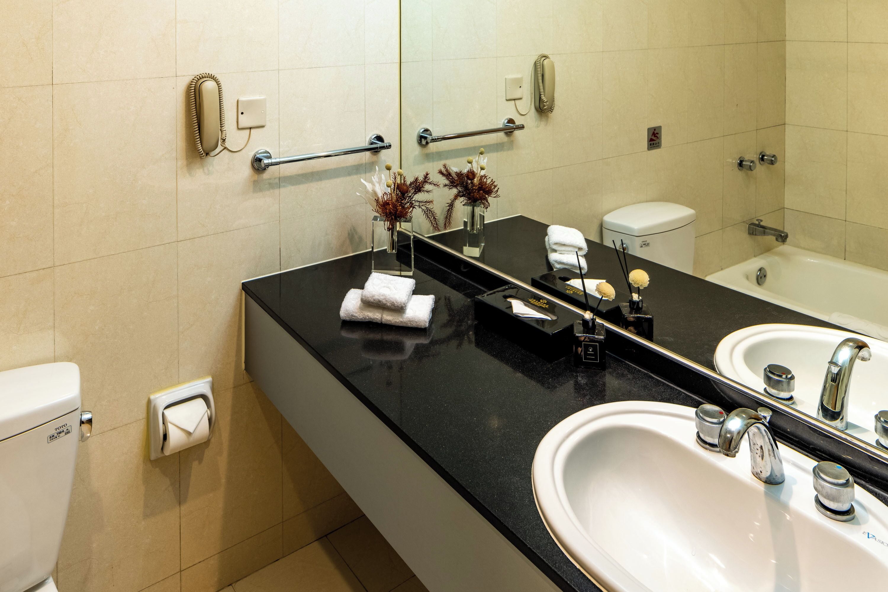 A modern bathroom with a black countertop, two sinks, a toilet, and a bathtub.