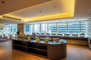 A modern hotel lobby with a central island, seating area, and large windows offering city views. - Jin Jiang Tian Cheng Hotel (Shanghai)