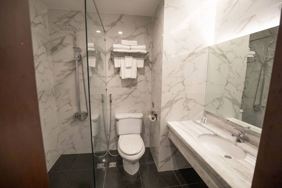 Une salle de bain moderne avec une douche en verre, des toilettes, un lavabo et un mur recouvert de carreaux de marbre.