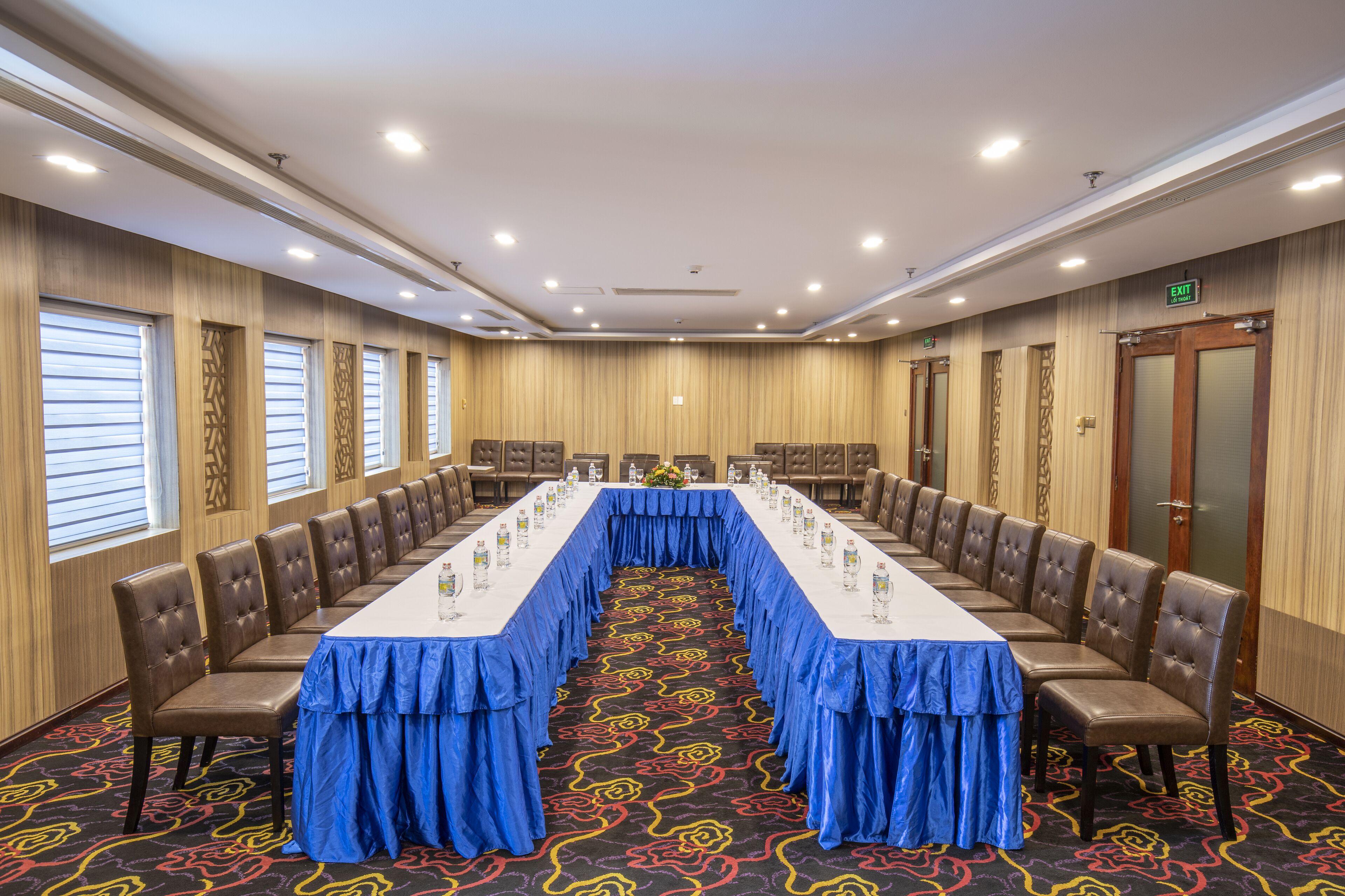 A conference room with a long table, chairs, and a carpeted floor.