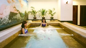 Un área de spa con un jacuzzi, plantas en macetas y un mural en la pared.