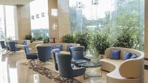 Un moderno vestíbulo con zonas de estar, ventanas amplias y plantas de interior.