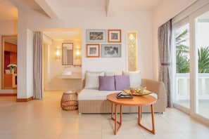 Una sala moderna con un sofá, una mesa de centro y una mesa de comedor. Hay cuadros en la pared, un espejo y vistas al exterior a través de grandes ventanales.