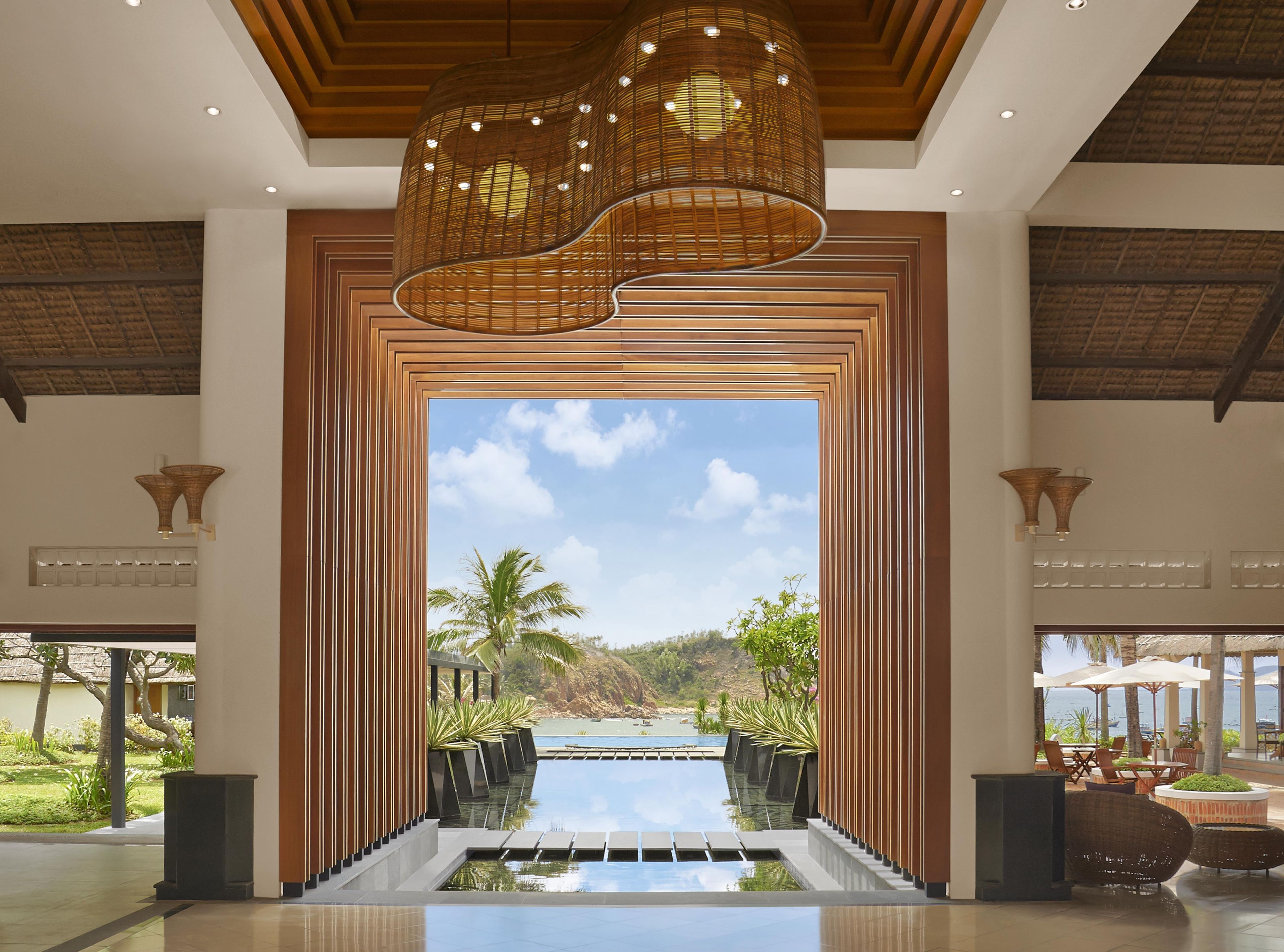 A modern hotel lobby with a large view of a pool and palm trees.
