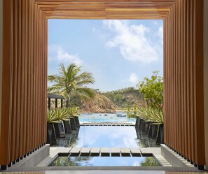 Piscina com vista para a praia e palmeiras.