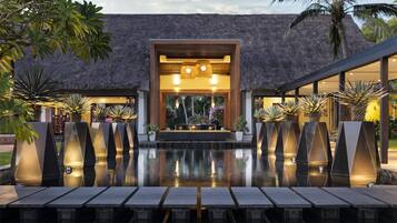 A modern resort with a pool, thatched-roof structure, and tropical plants.