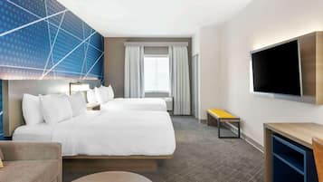 A hotel room with a large bed, a TV mounted on the wall, a small table, and a bench.