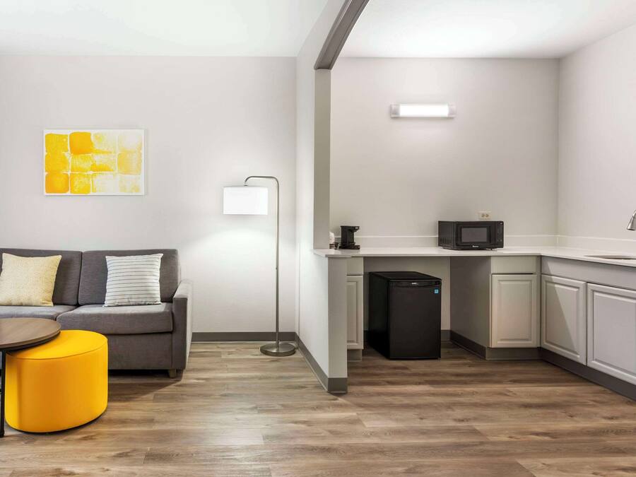 A compact living space with a kitchenette, a sofa, a small round table, and a floor lamp.