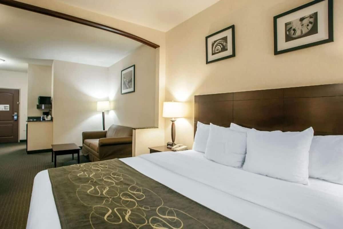 A hotel room with a bed, a desk, a chair, and a kitchenette.