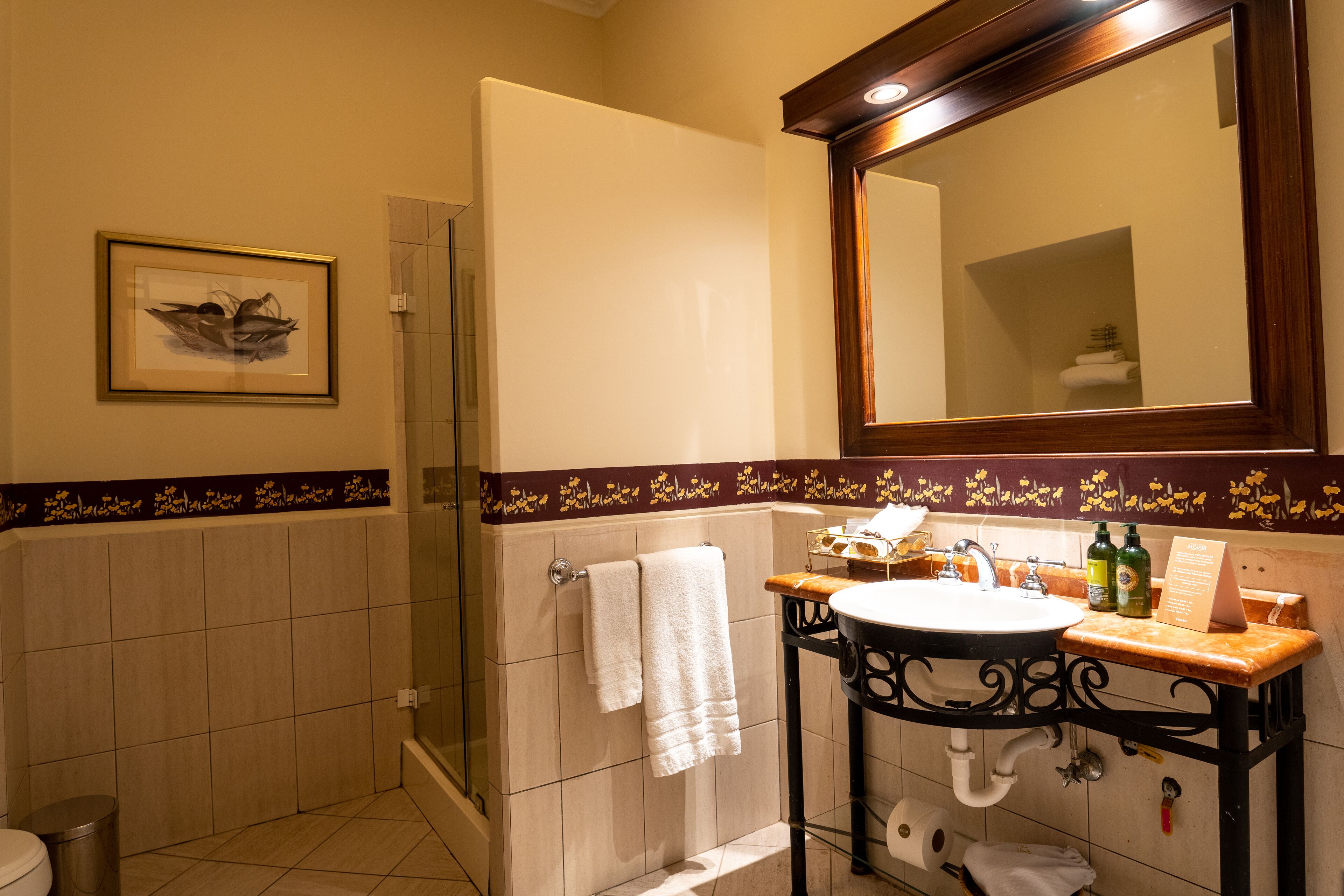 Un baño con ducha, lavamanos y espejo.