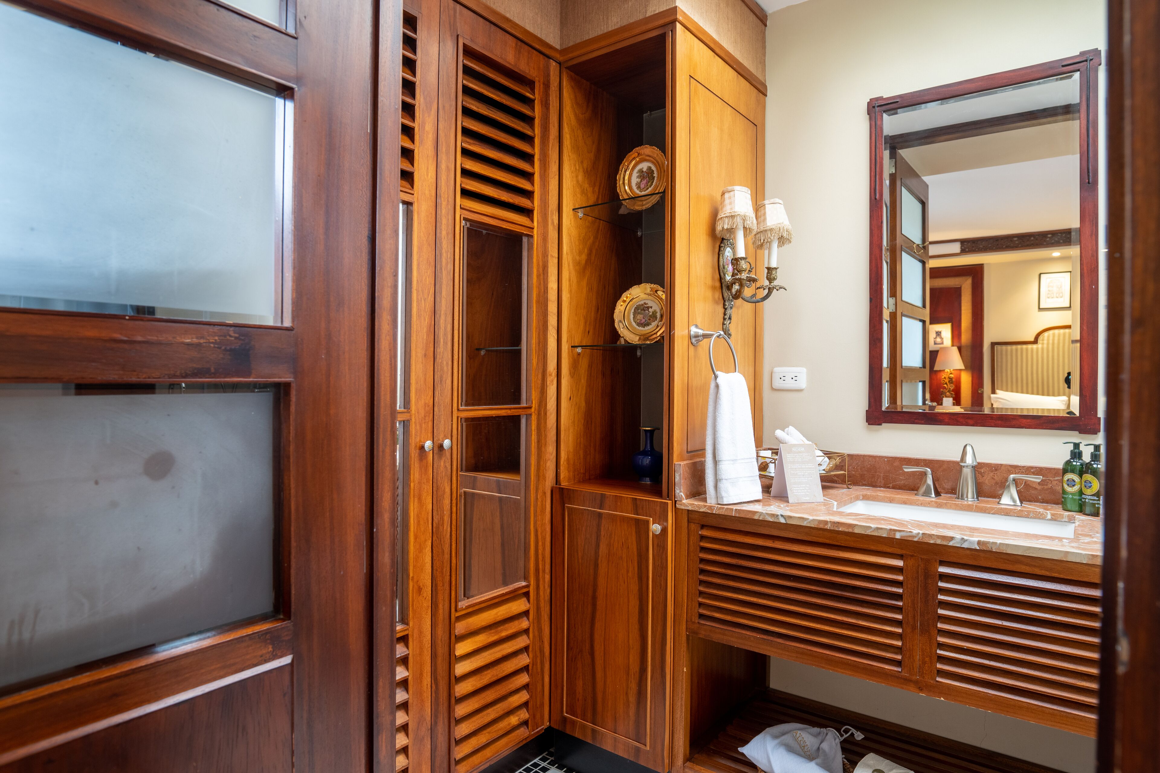 A wooden vanity with a large mirror, a sink, and a towel rack.