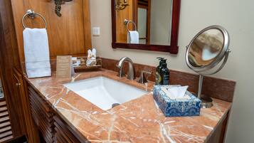 A bathroom with a marble sink, a mirror, a towel rack, and a box of tissues.
