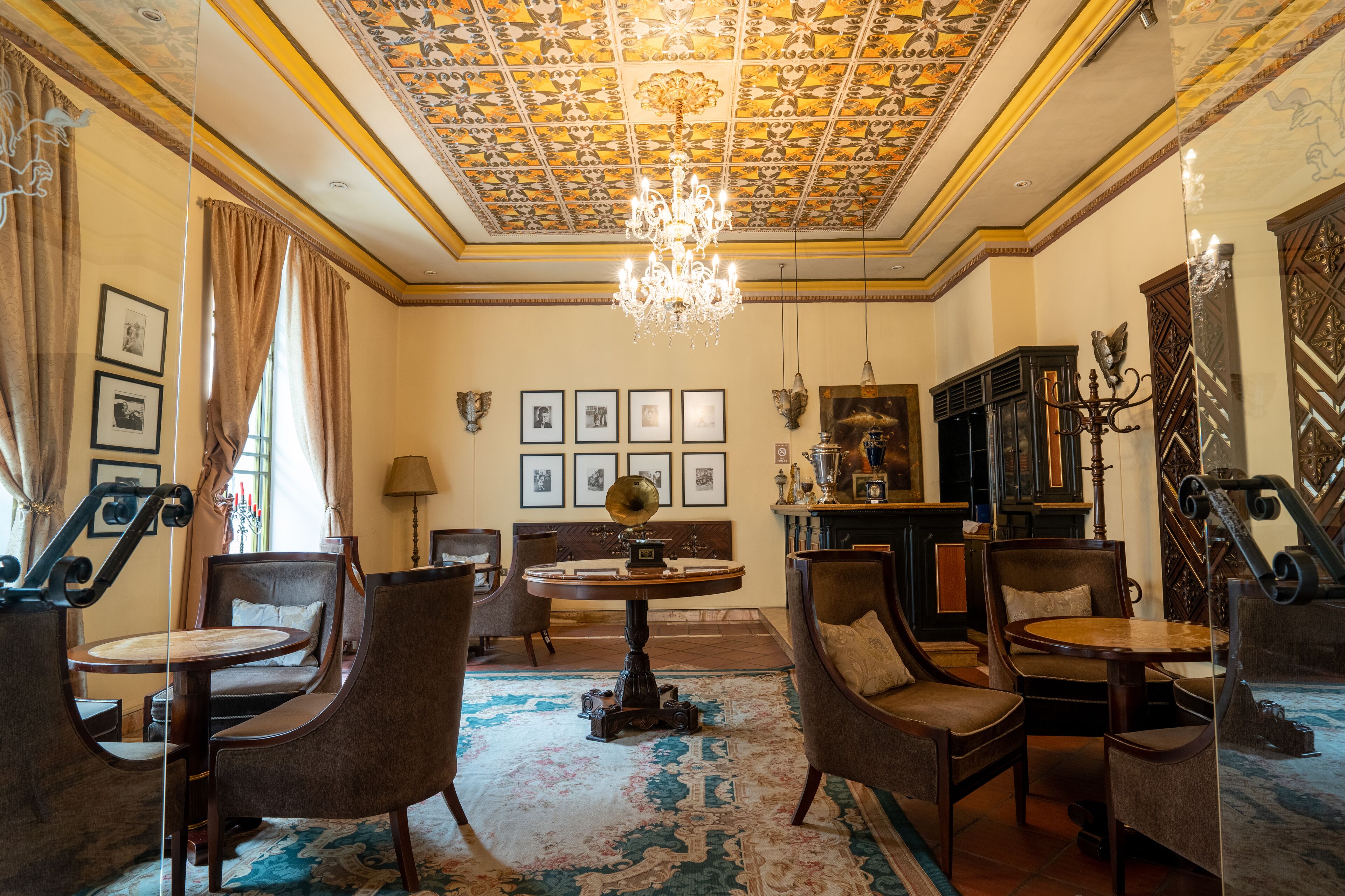 A room with a chandelier, framed pictures on the wall, and a globe on a table.