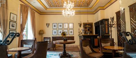 A room with a chandelier, framed pictures on the wall, and a globe on a table.