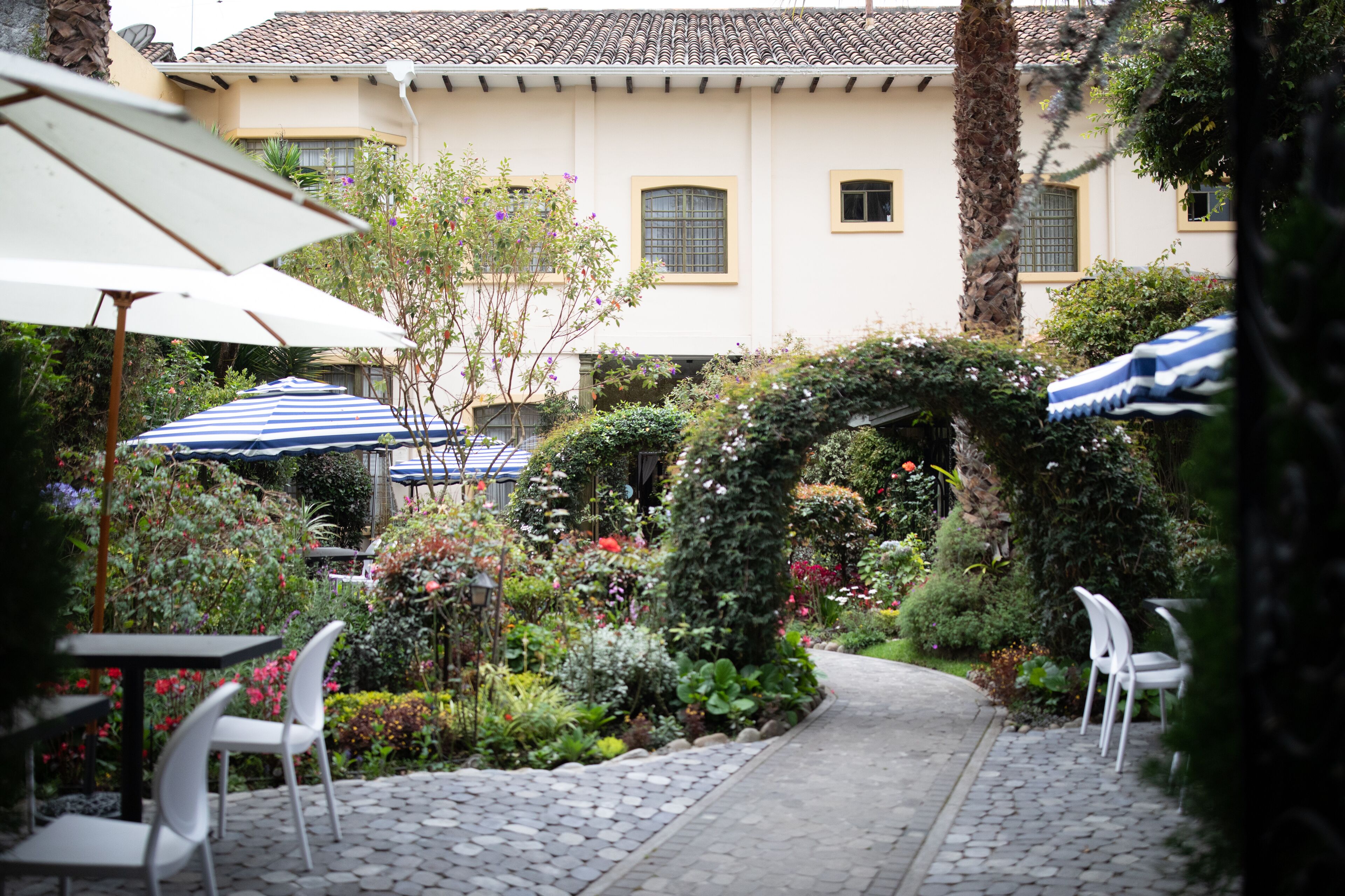 Une terrasse extérieure avec un sol en pierre, des chaises blanches et des parasols.