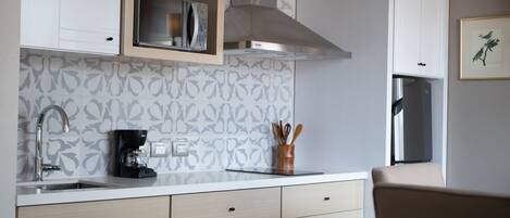A modern kitchen with white cabinetry, a stainless steel range hood, and a microwave.