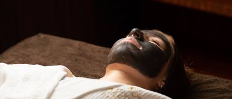 A person lying on a massage table with a white towel.