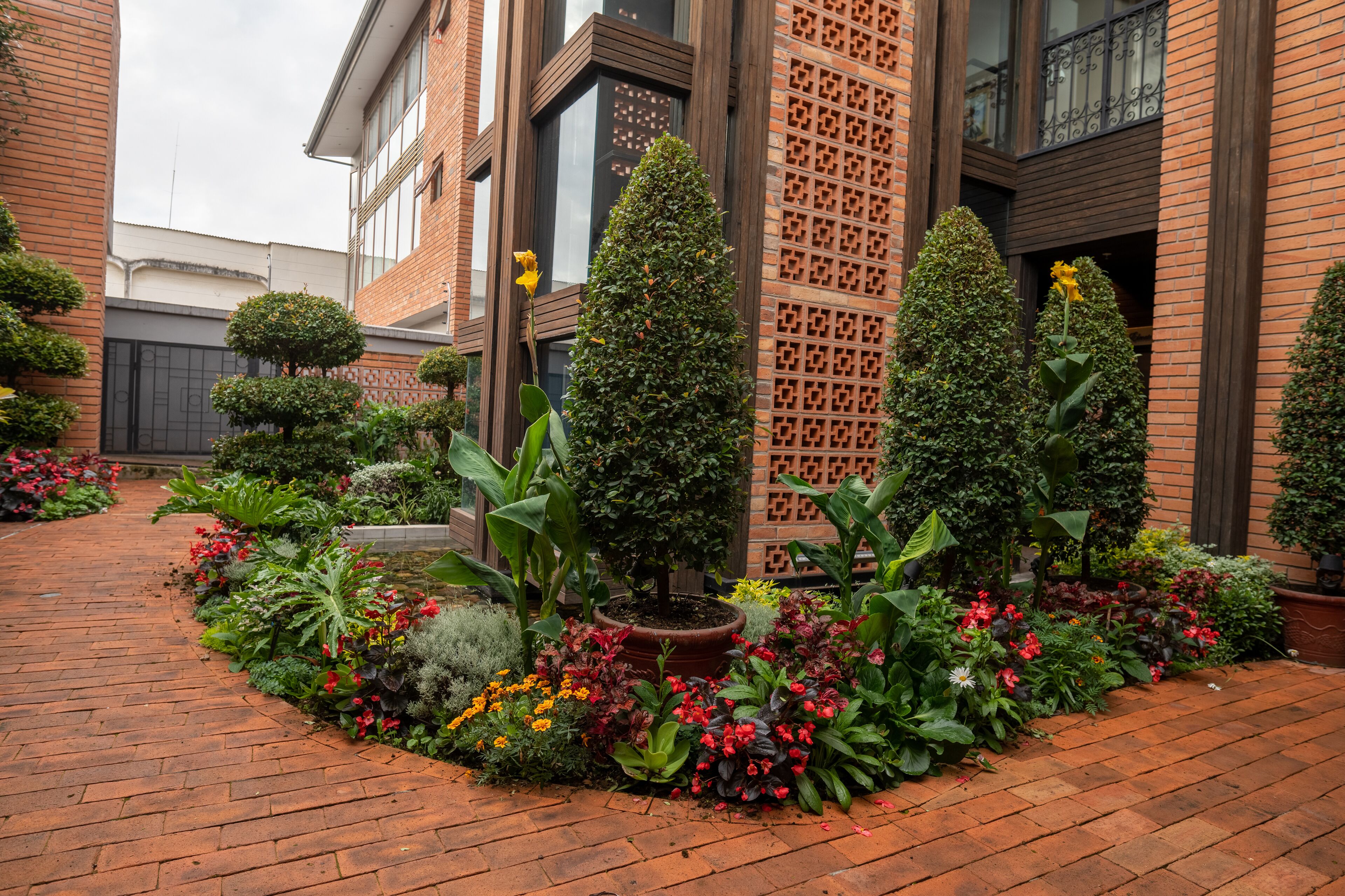 A brick building with a garden in front, featuring a variety of plants and flowers.