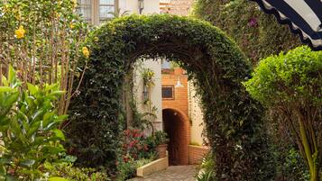 Stroll through the lush garden, lined with a brick archway and surrounded by vibrant flowers and greenery.