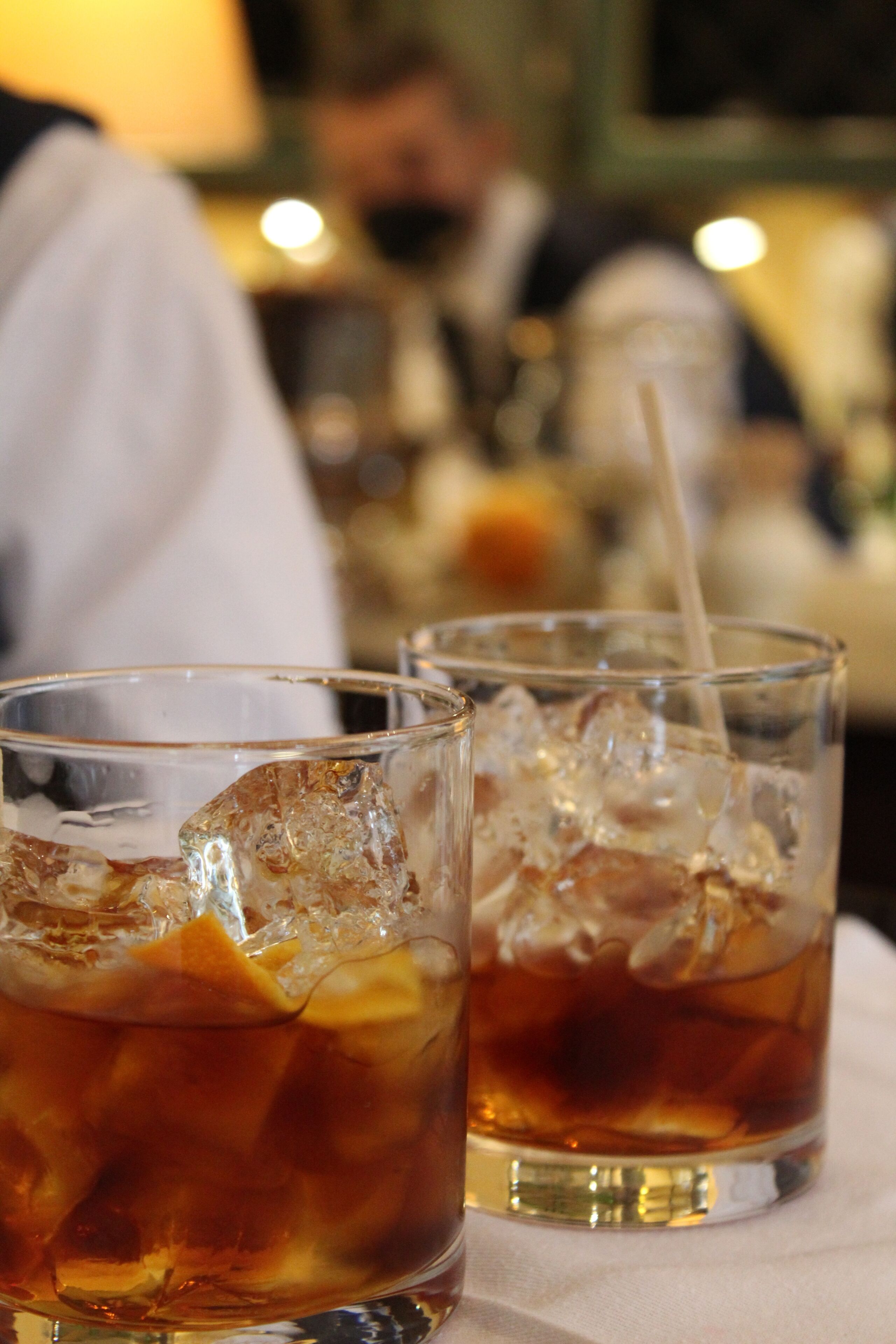 Two glasses of iced tea with ice cubes on a table.