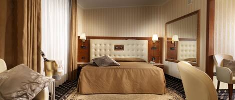 A hotel room with a large bed, two bedside tables with lamps, a chair, a large mirror, and a patterned carpet.