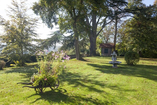 A garden with a statue, a small building, and a variety of trees and plants. - The Originals Boutique, Parc Hôtel, Orléans Sud (La Chapelle-Saint-Mesmin)