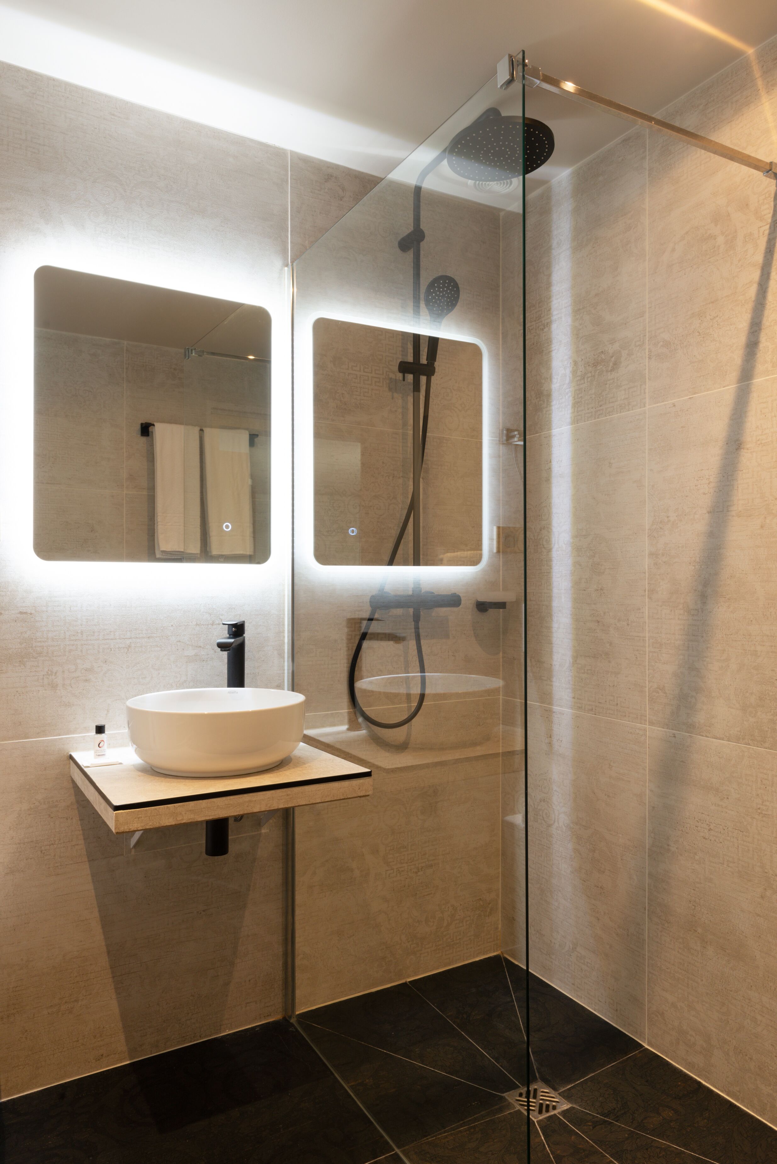 Un baño moderno con ducha de vidrio, un lavamanos blanco y un espejo encima.