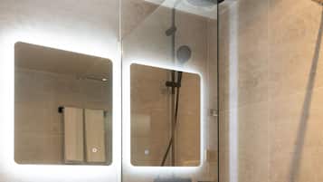 A modern bathroom with a glass-enclosed shower, a white sink, and a mirror above it.
