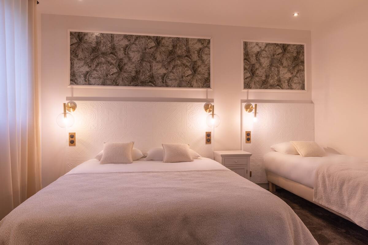 Quarto de hotel com duas camas, uma mesa de cabeceira e obras de arte penduradas na parede.