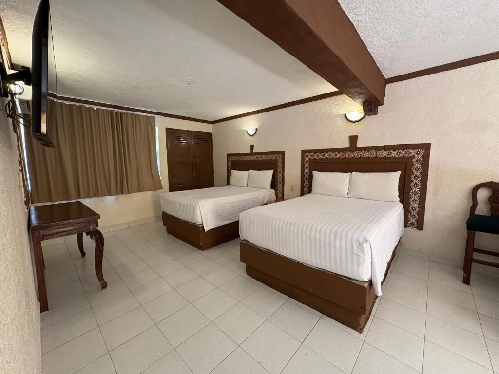 Une chambre d’hôtel avec deux lits, une télévision, un bureau et une chaise.