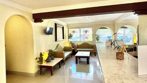 A spacious living area with a marble countertop, two sofas, a coffee table, and a TV mounted on the wall. - Suites Cancun Center Cancun (Cancun)