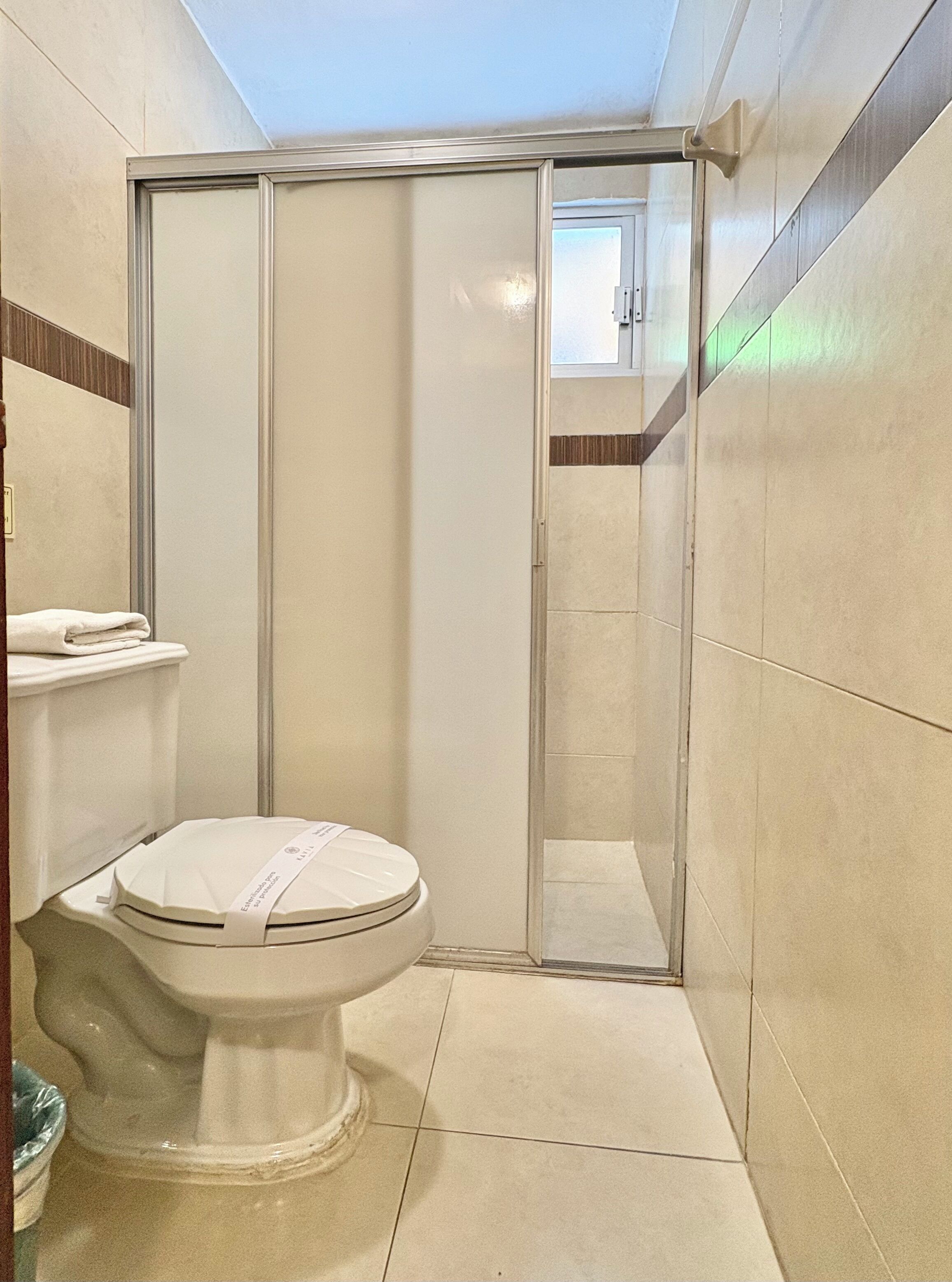 Un baño con inodoro, cabina de ducha y paredes de azulejos.