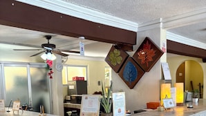 A reception desk with a marble counter, a ceiling fan, and a wall-mounted clock. - Suites Cancun Center Cancun (Cancun)