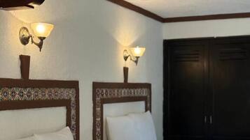 A hotel room with two beds, each with a headboard and a wall-mounted light fixture.