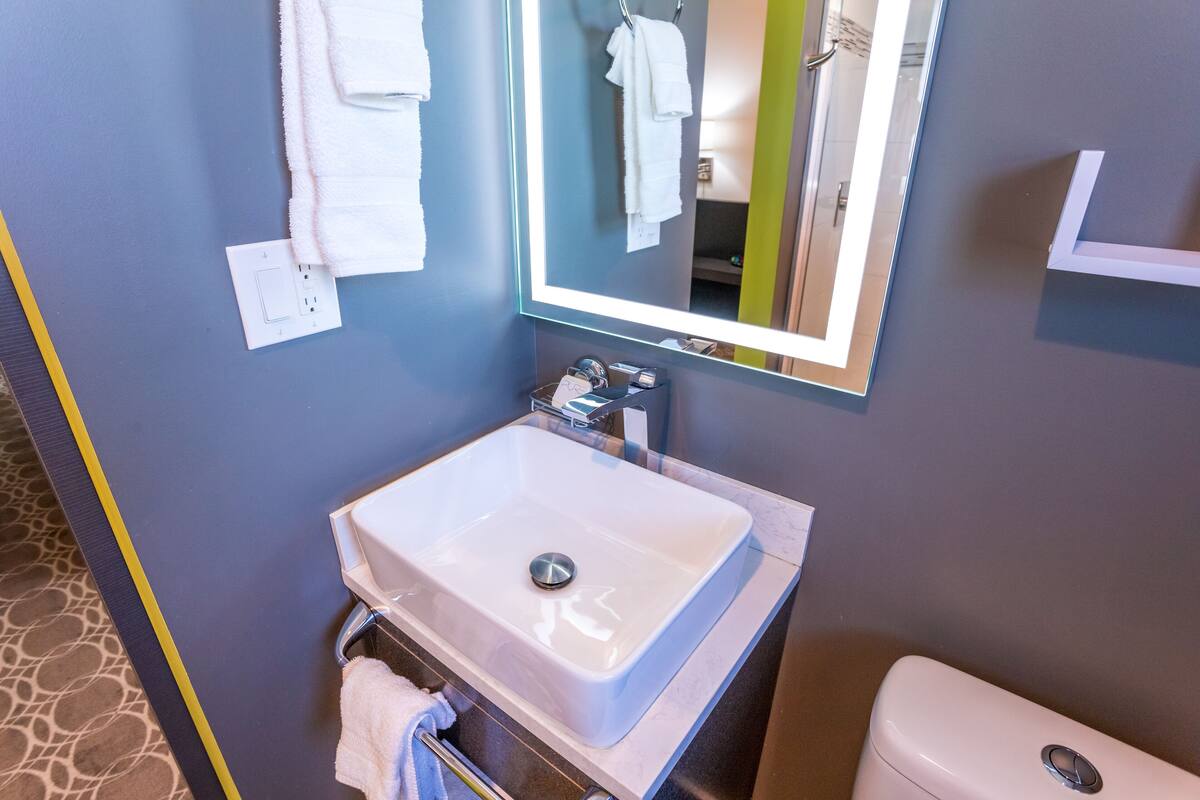 Une salle de bain avec un lavabo blanc, un miroir et des toilettes.